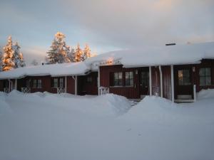 dom pokryty śniegiem z kupą śniegu w obiekcie Saariselän Marjamajat Apartment Sopuli w mieście Saariselkä