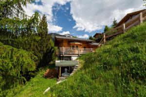 uma casa de madeira numa colina com uma encosta relvada em Jacuzzi & Sauna | Chalet Teremok em La Tzoumaz