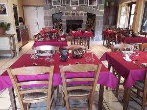 een eetkamer met rode tafels en stoelen en een open haard bij Auberge de l'Aspre in Fontanges