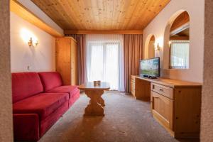 a living room with a red couch and a table at Hotel Garni Pfandl in Neustift im Stubaital
