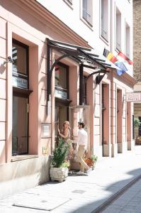 Dos mujeres están de pie fuera de un edificio rosa en Three Corners Hotel Art, en Budapest