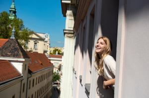 Eine Frau, die aus einem Fenster eines Gebäudes schaut. in der Unterkunft Three Corners Hotel Art in Budapest
