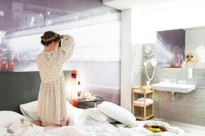a woman standing on a bed talking on a cell phone at Three Corners Hotel Anna in Budapest