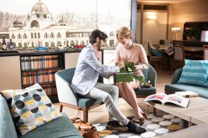 a man and woman in a living room holding a plant at Three Corners Hotel Art in Budapest