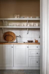 una cocina con armarios blancos y fregadero en Herba-ház, en Dánszentmiklós