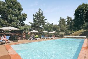 a swimming pool with people sitting in lawn chairs and umbrellas at Résidence Pierre & Vacances Les Trois Domaines in Ax-les-Thermes +40 photos