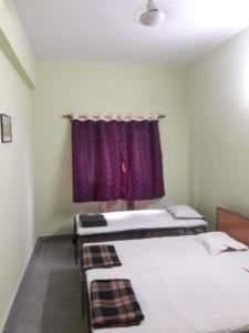 a room with two beds and a purple curtain at Capital Guest House in Kolkata