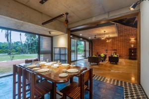 a large dining room with a table and a living room at SaffronStays Riverstone, Mysuru in Seringapatam