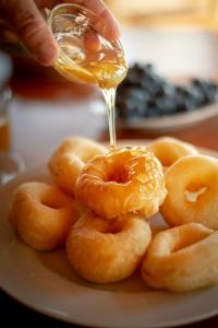 a person drizzling a glass of honey on a plate of donuts at Nashos Bungalows in (( Spile ))