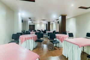 Hotel Gulmohar Grand في جورهات: غرفة بها طاولات وكراسي وردية وبيضاء