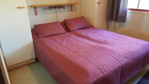 Bett in einem kleinen Zimmer mit lila Daunendecke in der Unterkunft Saariselän Marjamajat Apartment Sopuli in Saariselkä