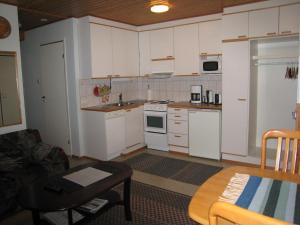 a small kitchen with white cabinets and a table at Saariselän Marjamajat Apartment Sopuli in Saariselka