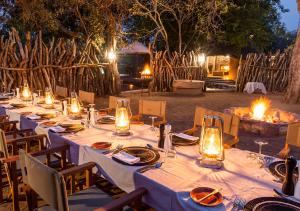 una mesa larga con luces, platos y velas en aha Makalali Private Game Lodge, en Makalali Game Reserve