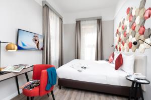 una camera con letto, scrivania e sedia rossa di Three Corners Hotel Art a Budapest