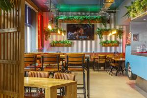 a restaurant with wooden tables and chairs and plants at Kick Ass Greyfriars (18+) in Edinburgh