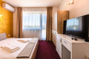 a hotel room with a bed and a flat screen tv at Guest House Theona in Obzor