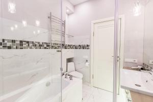 a white bathroom with a tub and a toilet and a sink at SutkiMinsk Economy in Minsk