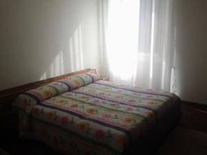 ein Bett mit einer Decke vor einem Fenster in der Unterkunft Cardinal Tivoli Trevio in Tivoli