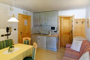 eine Küche und ein Wohnzimmer mit einem Tisch und einem Sofa in der Unterkunft Apartments Residence Montana in Oberrasen