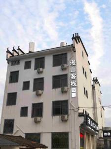 un bâtiment blanc avec un panneau sur son côté dans l'établissement Wuyuan Man Shan Inn, à Wuyuan