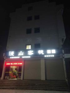 un bâtiment avec un panneau à l'avant de celui-ci la nuit dans l'établissement Wuyuan Man Shan Inn, à Wuyuan