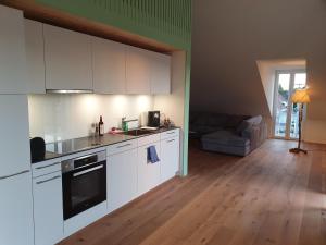 a kitchen with white cabinets and a living room at Wohnstation President Suite in Subingen