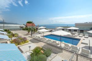 - une piscine avec chaises longues et parasols et l'océan dans l'établissement Apartments Kamelija, à Split