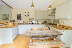 uma cozinha com armários brancos e uma mesa e cadeiras de madeira em Robin Hood Farm B&B em Baslow