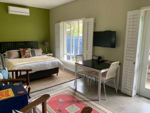 Schlafzimmer mit einem Bett, einem Tisch und einem TV in der Unterkunft Frida’s Place - Quiet in Stellenbosch Central in Stellenbosch