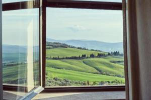 a window with a view of a green field at Il Torrino - Daria Monticchiello in Pienza