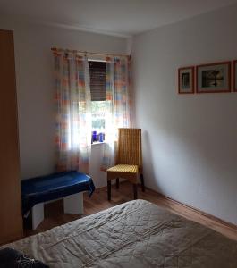 1 dormitorio con 1 cama, 1 silla y 1 ventana en Ferienwohnung S. Armbruster, en Bernsbach