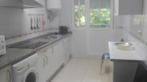cocina blanca con fregadero y lavadora en Apartamento Los conquistadores., en Sanlúcar de Barrameda