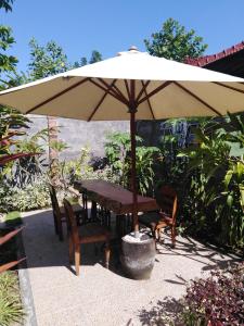a wooden table and chairs under an umbrella at Murnis Bungalow in Lovina