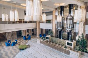 a lobby with blue chairs and large chandeliers at Iberostar Selection Kuriat Palace in Monastir