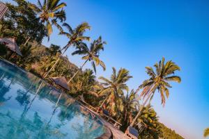 una piscina con palmeras en el fondo en Puri Sunny Camp, en Munduk