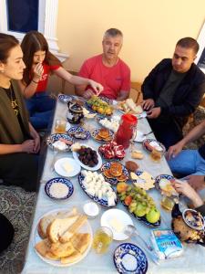 un grupo de personas sentadas alrededor de una mesa llena de comida en PARVIZ GUEST HOUSE, en Bukhara