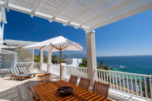 a patio with a table with an umbrella and the ocean at Felsensicht Holiday Home in Simonʼs Town