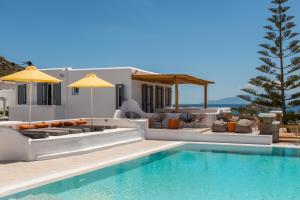 a patio area with a pool, chairs, and a large umbrella at Artemoula's Studios in Platis Gialos
