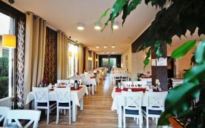 a dining room with white tables and chairs at Bursztyn Resort in Kołobrzeg