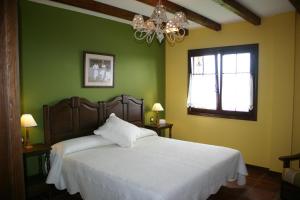 Un dormitorio con una cama blanca con paredes verdes y una lámpara de araña. en Eco Hotel Rural Lurdeia - Adults Only en Bermeo