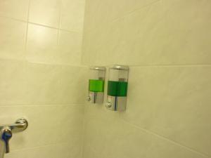 ein Bad mit einer Dusche mit grünen und weißen Fliesen in der Unterkunft Apartmán VAN NG in Prag