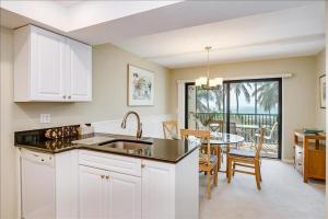 a kitchen with white cabinets and a dining room with a table at Sea Oats 236 Apartment in Boca Grande