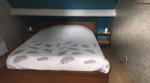 ein Bett mit einer weißen Decke mit Palmen darauf in der Unterkunft chambre proche du circuit des 24h in Mulsanne