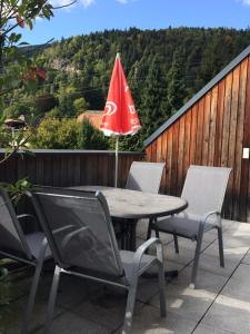 einen Tisch und Stühle mit einem roten Regenschirm auf einer Terrasse in der Unterkunft Ferienwohnung Frieser in Steindorf am Ossiacher See