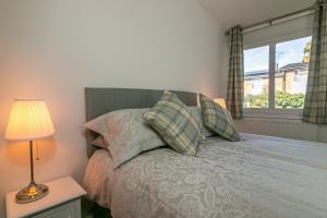 a bedroom with a bed with a lamp and a window at Hillcrest Lodge in Stevenage