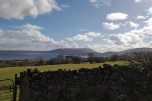 a stone wall with a view of the water and mountains at Groff Cottage in Toormakeady +7 photos