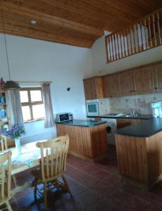 a kitchen with wooden cabinets and a table and chairs at Groff Cottage in Toormakeady