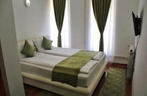 a bedroom with a bed with a green blanket on it at Hotel Fontana in Zenica