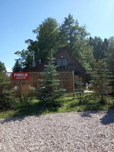 une cabane en rondins avec une clôture et quelques arbres dans l'établissement Chata Baby Jagi, à Krzywe