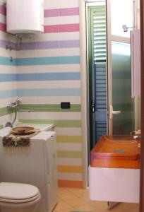a bathroom with a toilet and a colorful striped wall at Villa Mare Noto Marina in Noto Marina